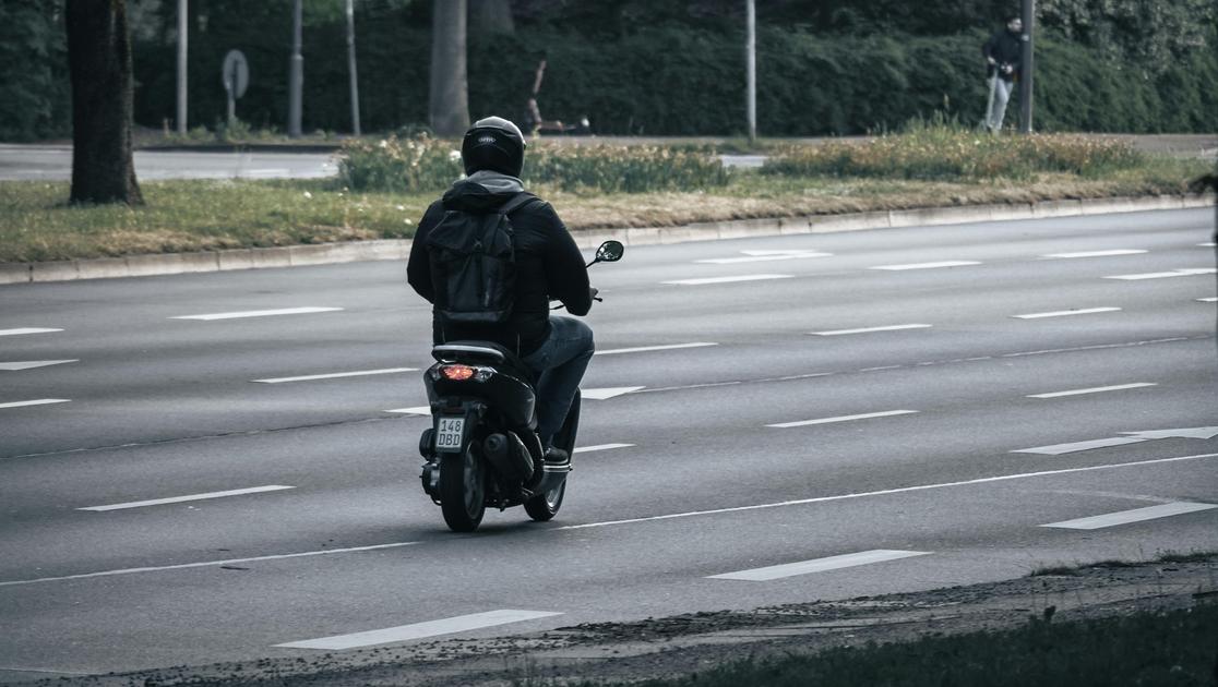 Un uomo su uno scooter con un casco.