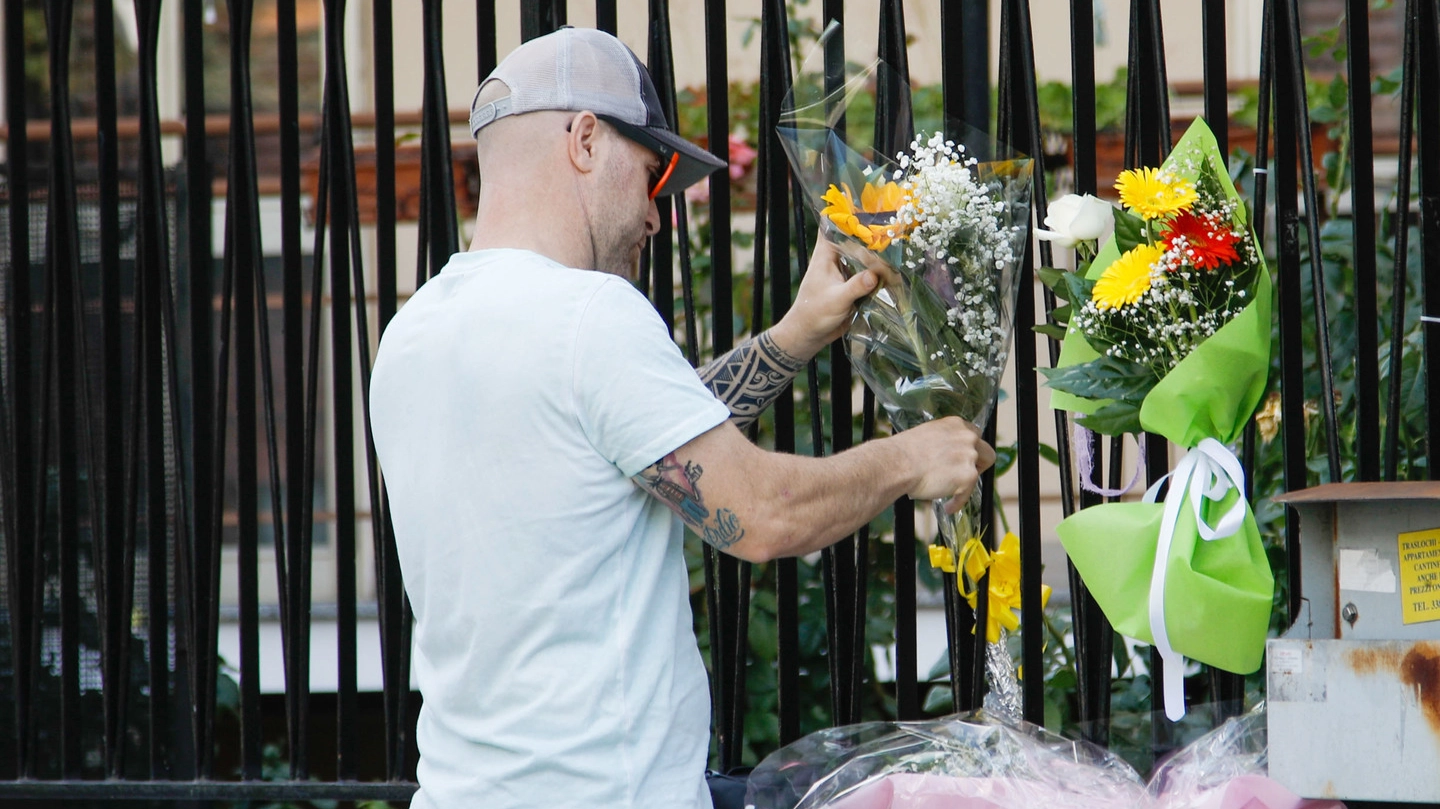 Un uomo attacca un mazzo di fiori al cancello del condominio di corso Roma 100, dove Sofia è stata uccisa all’alba di sabato