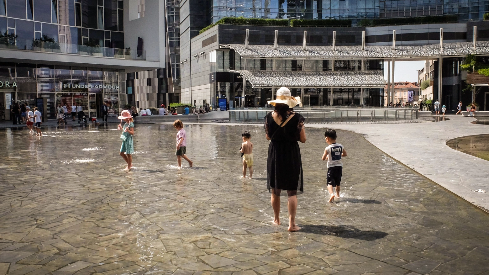 Alcuni bambini si rinfrescano nelle fontane di piazza Gae Aulenti a Milano (Ansa/Matteo Corner)