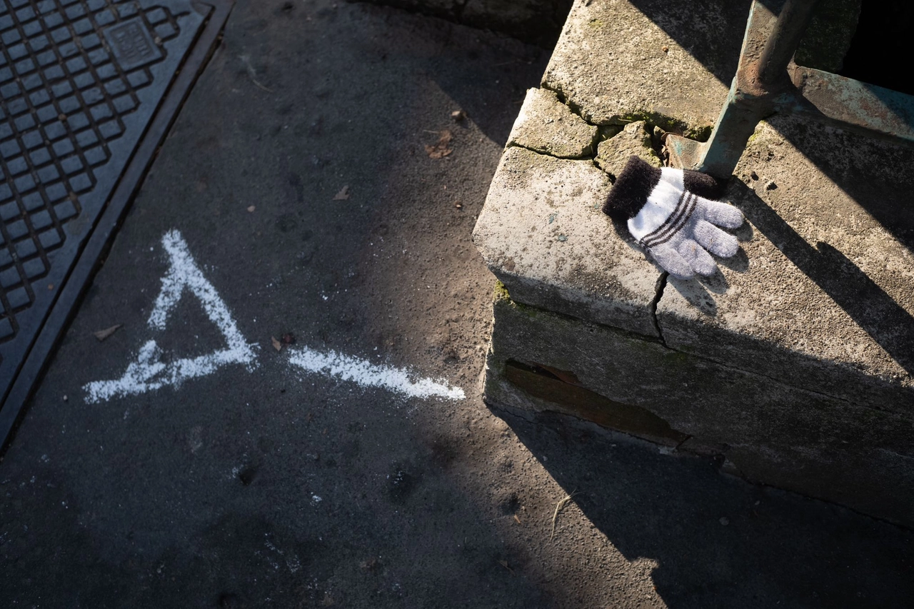 I rilievi della polizia locale sul posto. A destra, il guantino di uno dei bambini (Ansa/Davide Canella)