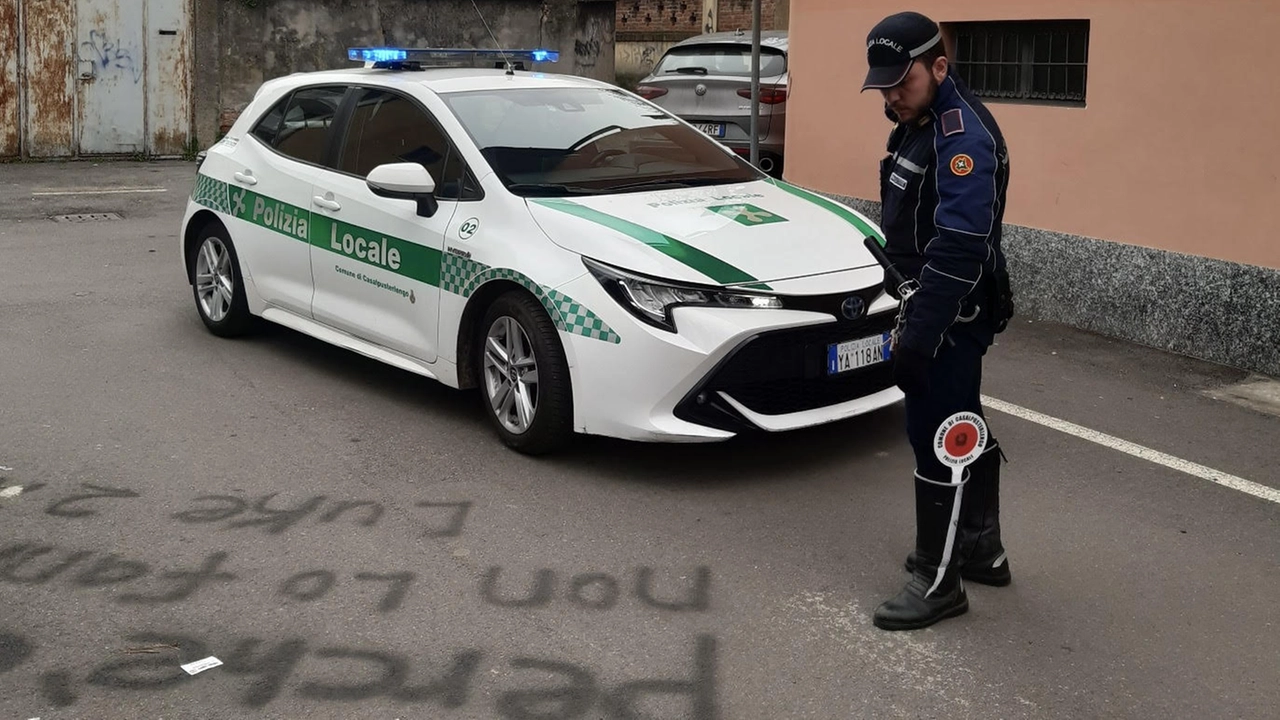 Un agente della polizia locale di Casalpusterlengo osserva una delle scritte tracciate sull'asfalto e su un muro della chiesa