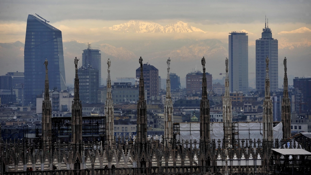 Lo skyline di Milano con in primo piano le guglie del Duomo, la torre Diamante e il grattacielo Pirelli e sullo sfondo le Alpi