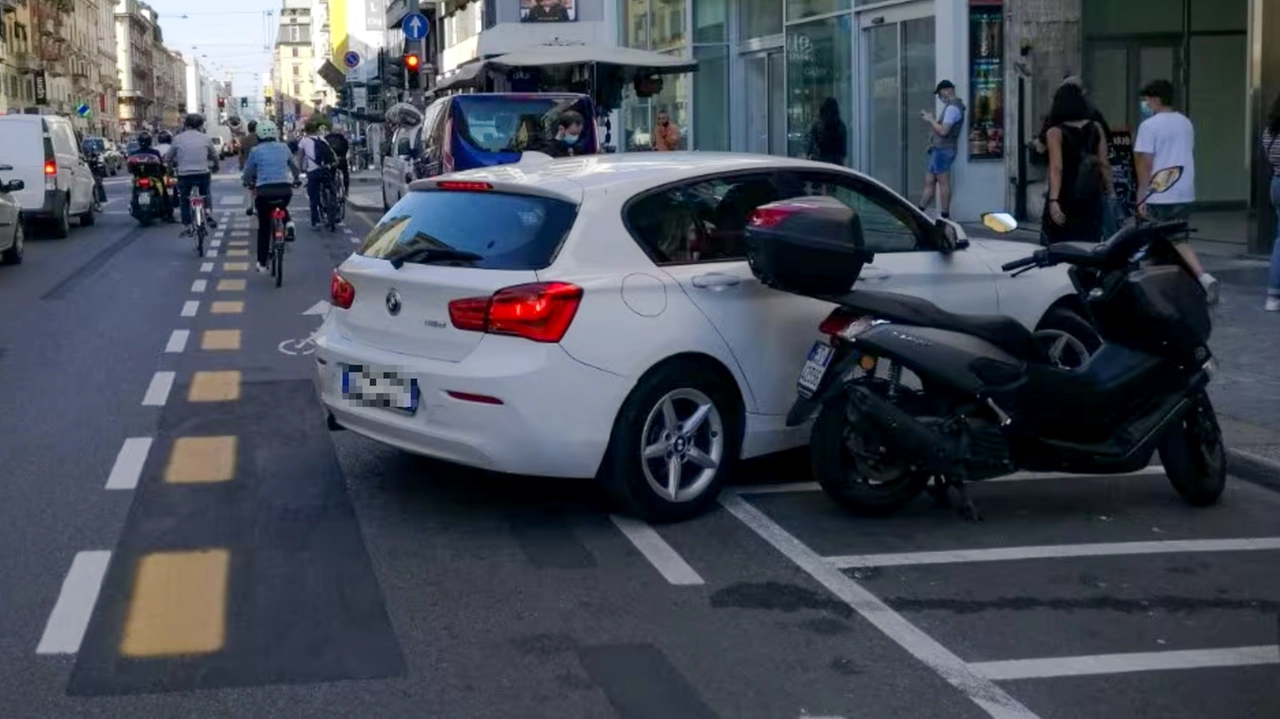 Un'auto parcheggiata in una sosta per motoveicoli invade una pista ciclabile