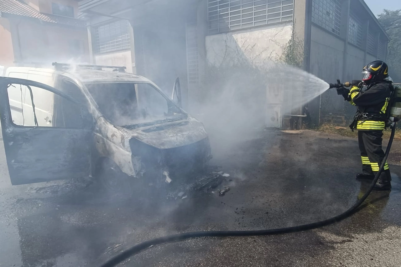 Un vigile cerca di domare le fiamme che hanno interessato un mezzo parcheggiato vicino allo stadio Speroni