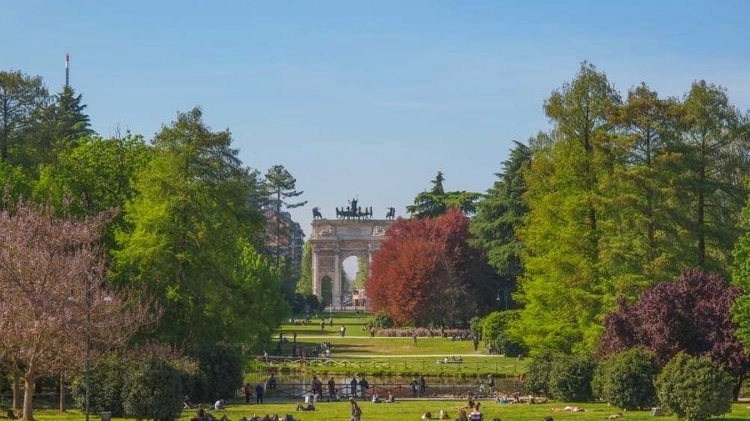 A sinistra, persone che frequentano il Parco Sempione e, sullo sfondo, l’Arco della Pace