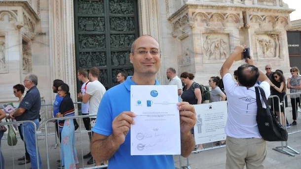 Giovanni Cafaro mostra il contratto collettivo nazionale da codista davanti al Duomo di Milano