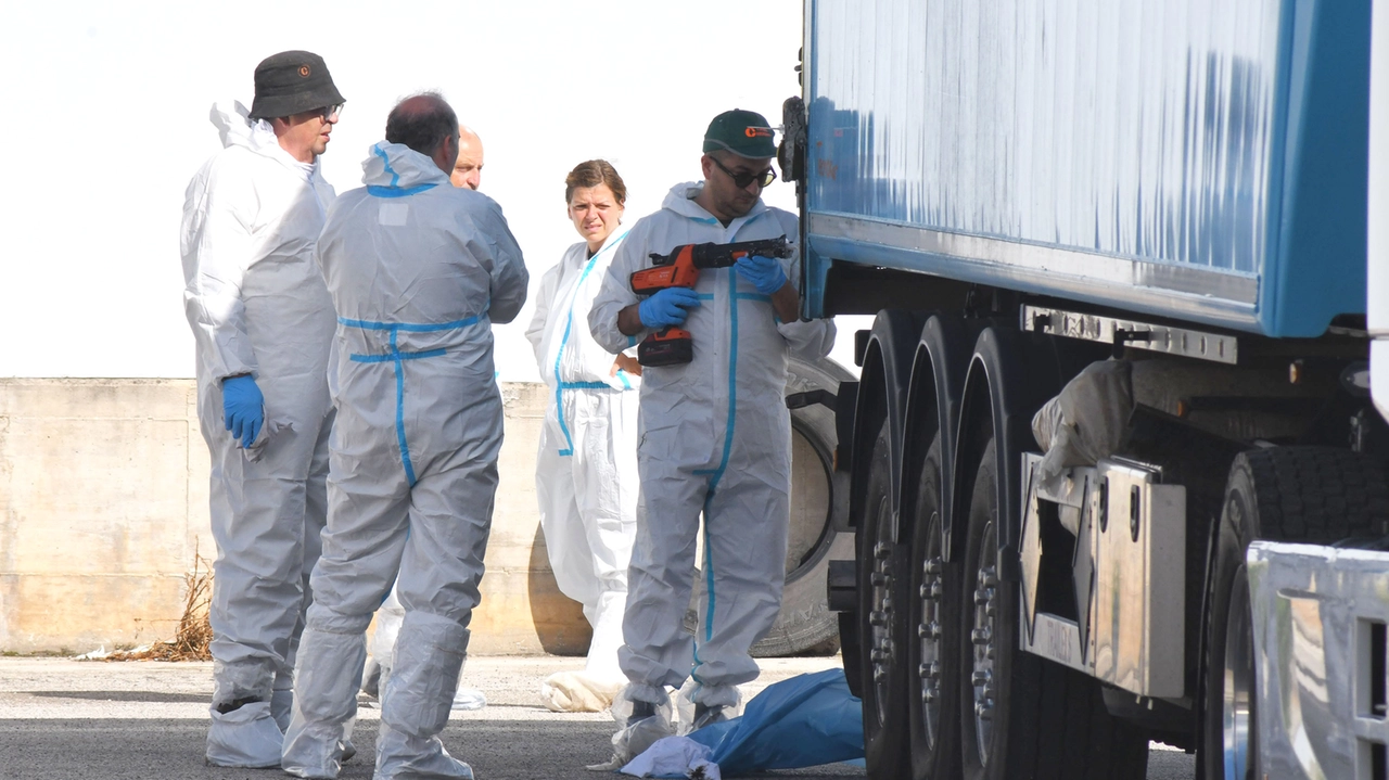 Gli operatori con le tute protettive al lavoro vicino al container