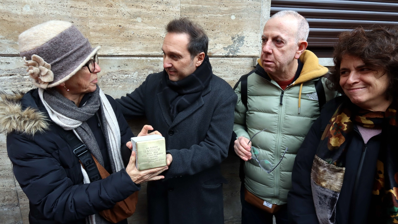 Luca Bragalini con i parenti di Renato arrivati da tutto il mondo e la pietra d'inciampo (foto Ansa/Salmoirago)